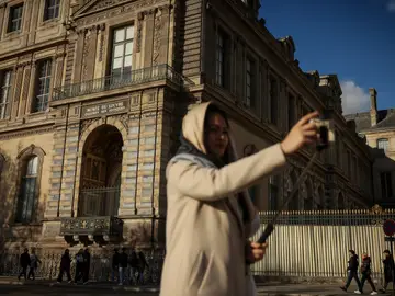 France Louvre A woman makes a selfie in front of the facade and the window where thieves entered the Louvre museum last Sunday, Saturday, Oct. 25, 2025 in Paris. (AP Photo/Thomas Padilla)