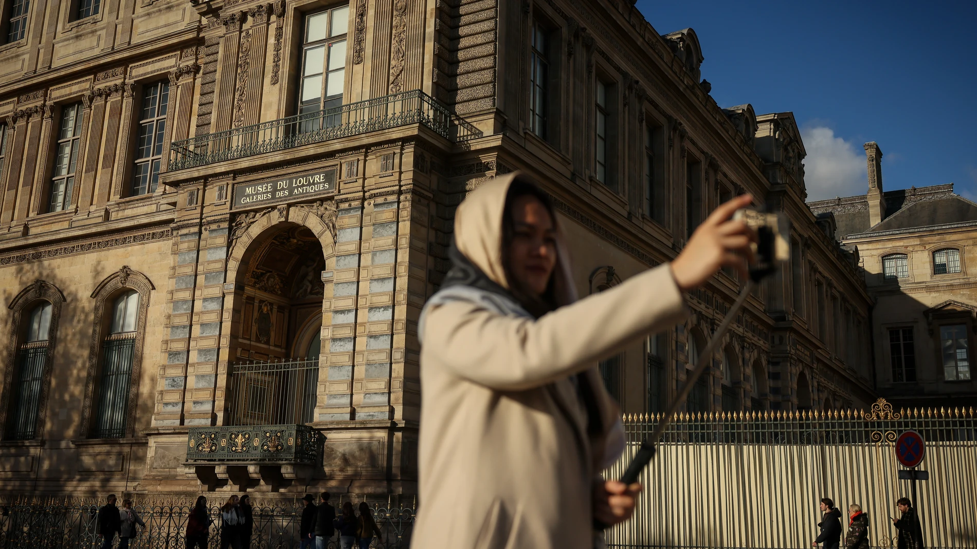 A woman makes a selfie in front of the facade and the window where thieves entered the Louvre museum last Sunday, Saturday, Oct. 25, 2025 in Paris. (AP Photo/Thomas Padilla)