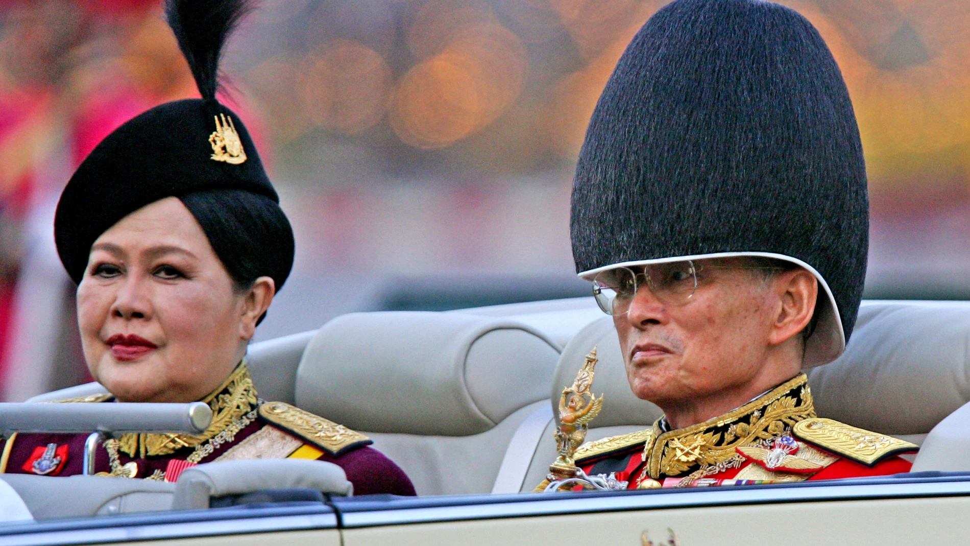 FILE - Late Thai King Bhumibol Adulyadej, right, and then Queen Sirikit attend the annual military parade to celebrate the king's 79th birthday in Bangkok Dec. 2, 2006. Sirikit Kitiyakara, who supervised royal projects to help the rural poor, preserve traditional craft-making and protect the environment, died on Friday, Oct. 24, 2025. She was 93. (AP Photo/Sakchai Lalit, File)
