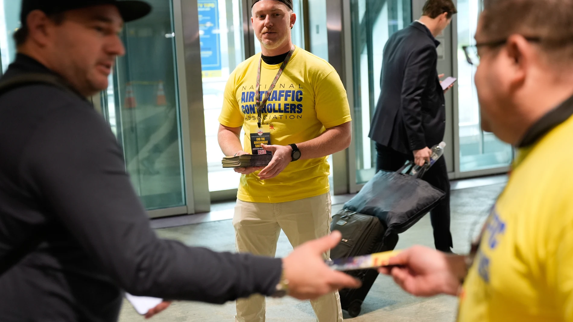 Air traffic controllers, including Matthew Hegel, center, hand out pamphlets urging travelers to contact their representatives to help stop the government shutdown at LaGuardia Airport in New York, Tuesday, Oct. 28, 2025. (AP Photo/Seth Wenig)