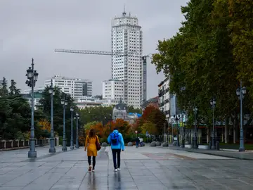 Día nuboso en la Comunidad de Madrid MADRID, 30/10/2025.- Dos viandantes pasan cerca del Palacio Real este jueves en el centro de Madrid. La Agencia Estatal de Meteorología (Aemet) prevé para este jueves en la Comunidad de Madrid una retirada de las lluvias con cielos nubosos y temperaturas mínimas que experimentarán un ligero descenso. EFE/Marisca