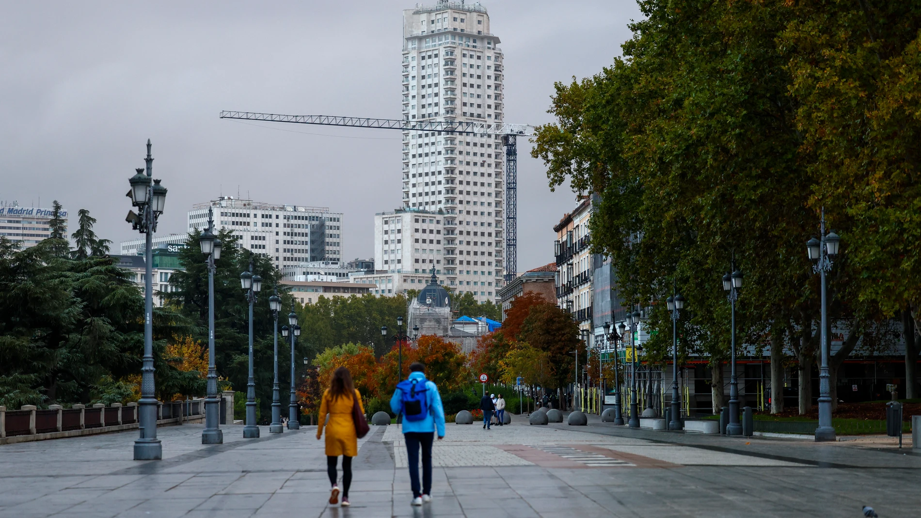 MADRID, 30/10/2025.- Dos viandantes pasan cerca del Palacio Real este jueves en el centro de Madrid. La Agencia Estatal de Meteorología (Aemet) prevé para este jueves en la Comunidad de Madrid una retirada de las lluvias con cielos nubosos y temperaturas mínimas que experimentarán un ligero descenso. EFE/Marisca
