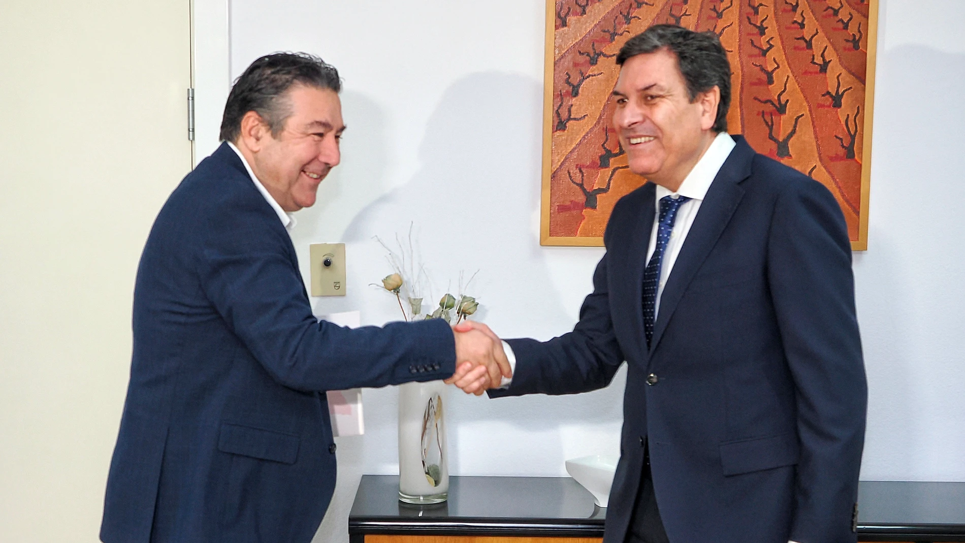 El consejero de Economía y Hacienda, Carlos Fernández Carriedo, saluda al líder de la UPL, Luis Mariano de Santos, en una reunión anterior