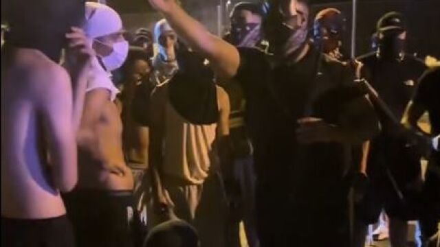 Grupos de magrebíes con capuchas durante los incidentes atienden la arenga del cabecilla, «Batmoro»