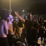 Grupos de magrebíes con capuchas durante los incidentes atienden la arenga del cabecilla, «Batmoro»