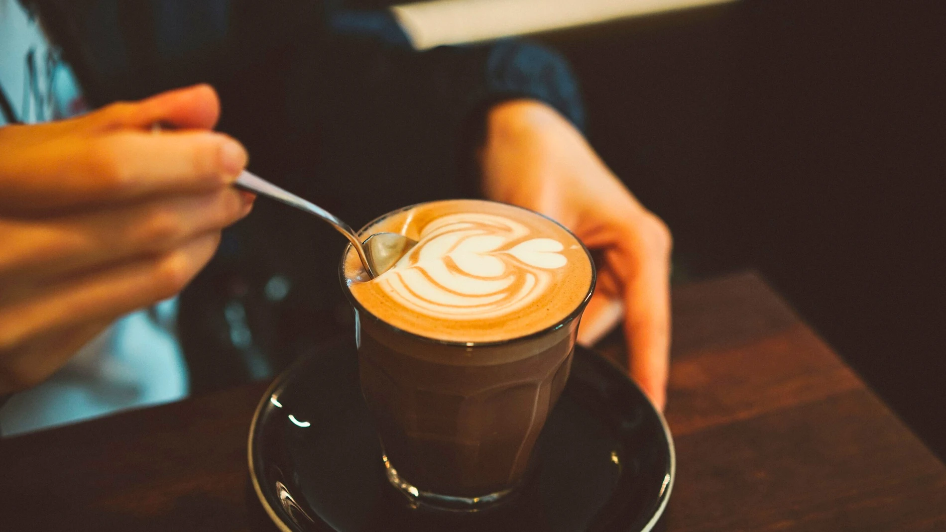 Una mano mueve su taza de café, un alimento clave en depresión