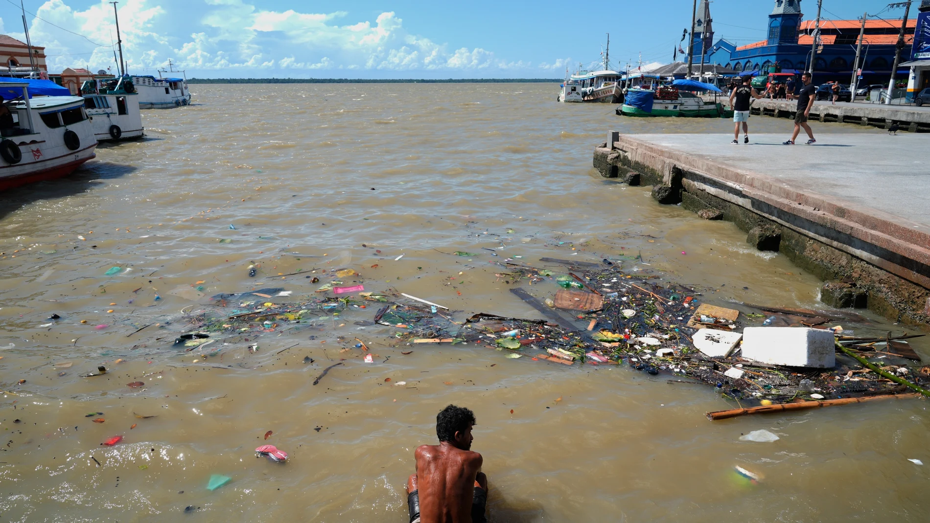 A man sits in a river amid the nearby COP30 U.N. Climate Summit, Saturday, Nov. 8, 2025, in Belem, Brazil. (AP Photo/Fernando Llano)