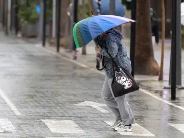 Una peonas cubriéndose del temporal con un paraguas Una peonas cubriéndose del temporal con un paraguas