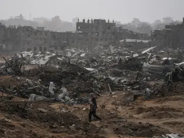 Israel Palestinians Gaza A Palestinian woman walks through a rainstorm past buildings destroyed in Israeli strikes in the Sheikh Radwan neighborhood of Gaza City, Friday, Nov. 14, 2025. (AP Photo/Jehad Alshrafi)