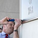 El secretario de Guerra, Pete Hegseth, termina de colocar uno de los carteles