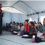 Estudiantes gazatíes asisten a clase dentro de una tienda de campaña instalada en la playa de Jan Yunis