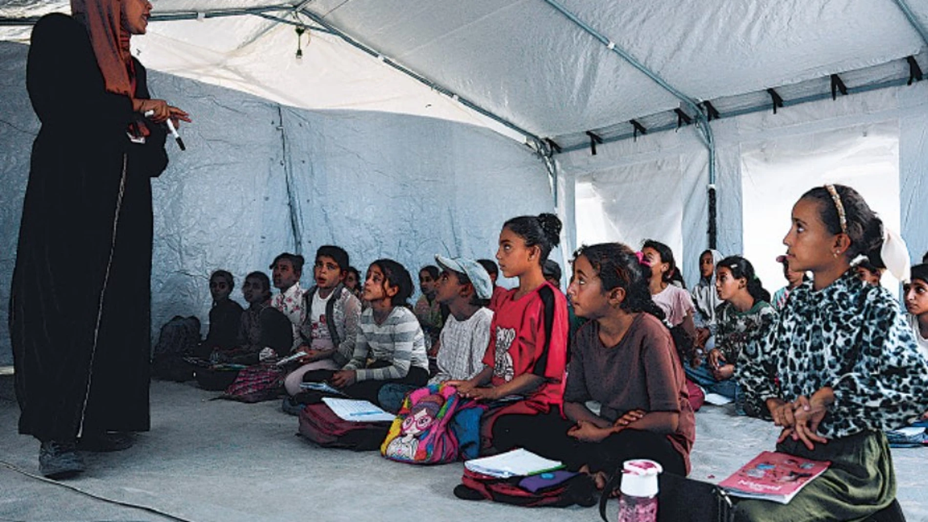 Estudiantes gazatíes asisten a clase dentro de una tienda de campaña instalada en la playa de Jan Yunis