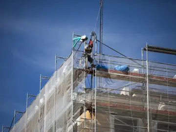 Un obrero en lo alto del andamio en un edificio en rehabilitación. en Madrid. Un obrero en lo alto del andamio en un edificio en rehabilitación. en Madrid.