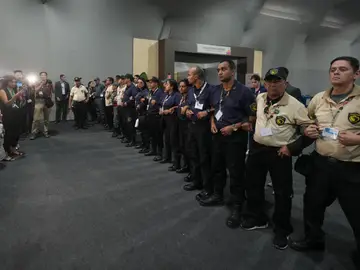 Climate COP30 Officials form a chain to not allow attendees past after attendees were asked to leave the venue for the COP30 U.N. Climate Summit, Thursday, Nov. 20, 2025, in Belem, Brazil. (AP Photo/Andre Penner)