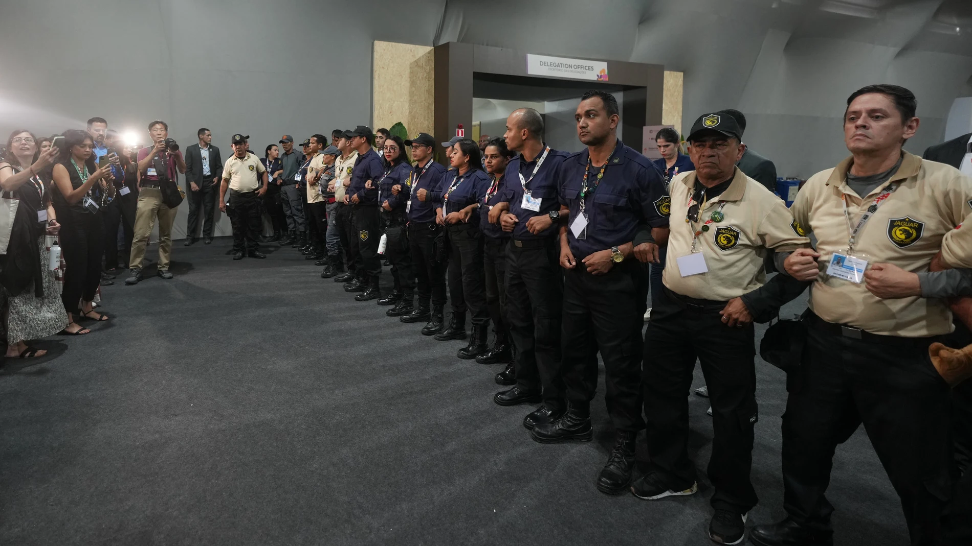 Officials form a chain to not allow attendees past after attendees were asked to leave the venue for the COP30 U.N. Climate Summit, Thursday, Nov. 20, 2025, in Belem, Brazil. (AP Photo/Andre Penner)