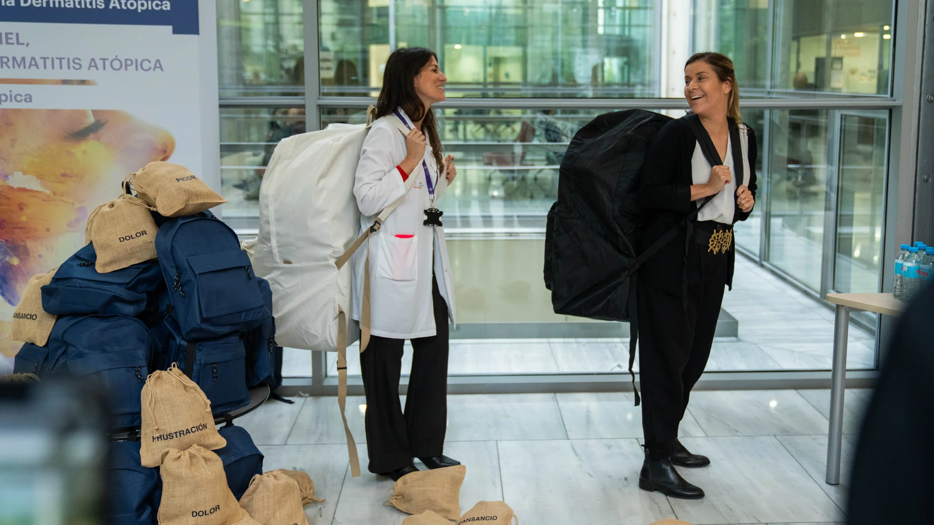 Sandra Ros, psicóloga, y África, paciente, llevan a cuestas la mochila que simula la carga emocional y mental que soportan los pacientes