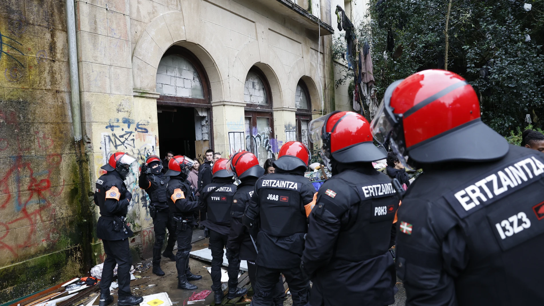 SAN SEBASTIAN, 04/12/2025.- Numerosos agentes de la Ertzaintza toman parte en el desalojo del antiguo colegio okupado del barrio de Martutene en San Sebastián en el que, según algunos colectivos, residían 111 personas, por lo que varias organizaciones sociales han convocado una concentración de protesta contra esta decisión judicial ante el Palacio de Justicia. EFE/Juan Herrero