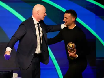 WCup Draw Soccer FIFA President Gianni Infantino, left, greets Argentina's coach Lionel Scaloni as he carries the Word Cup trophy during the match schedule reveal for the 2026 soccer World Cup in Washington, Saturday, Dec. 6, 2025. (AP Photo/Chris Carlson)