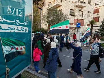 Sirios portan banderas en las celebraciones por el primer aniversario de la caída del régimen de Bachar al Asad Syrians wave flags as they march during weekend-long celebrations ahead of the first anniversary on Monday of the ousting of the Bashar Assad regime in Damascus, Syria, Saturday, Dec. 6, 2025. (AP Photo/Omar Sanadiki)