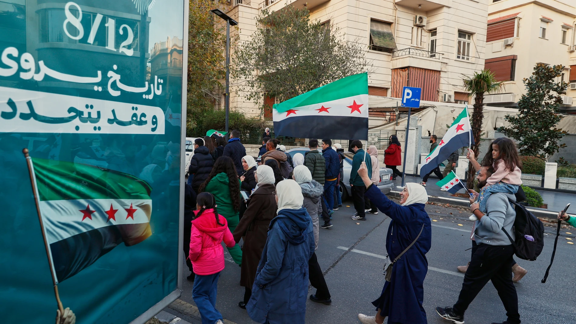 Syrians wave flags as they march during weekend-long celebrations ahead of the first anniversary on Monday of the ousting of the Bashar Assad regime in Damascus, Syria, Saturday, Dec. 6, 2025. (AP Photo/Omar Sanadiki)