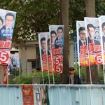 Ciudadanos hongkoneses pasan junto a carteles electorales en el distrito de Tai Po