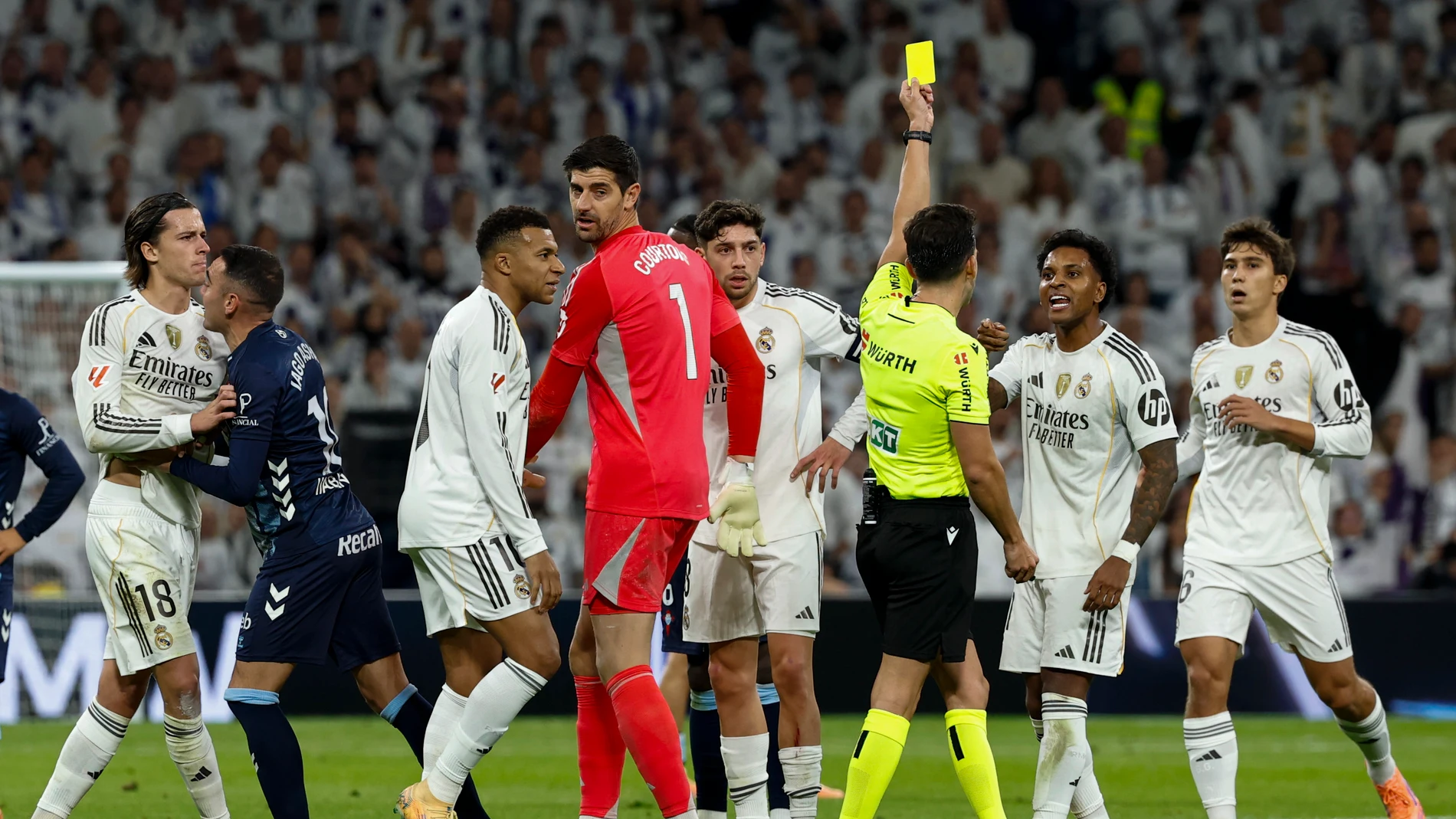 MADRID, 07/12/2025.- El árbitro Quintero González (3-d) muestra la tarjeta amarilla a Rodrygo Goes (2-d), del Real Madrid, durante el partido de LaLiga de fútbol que Real Madrid y Celta de Vigo han disputado este domingo en el estadio Santiago Bernabéu. EFE/Chema Moya