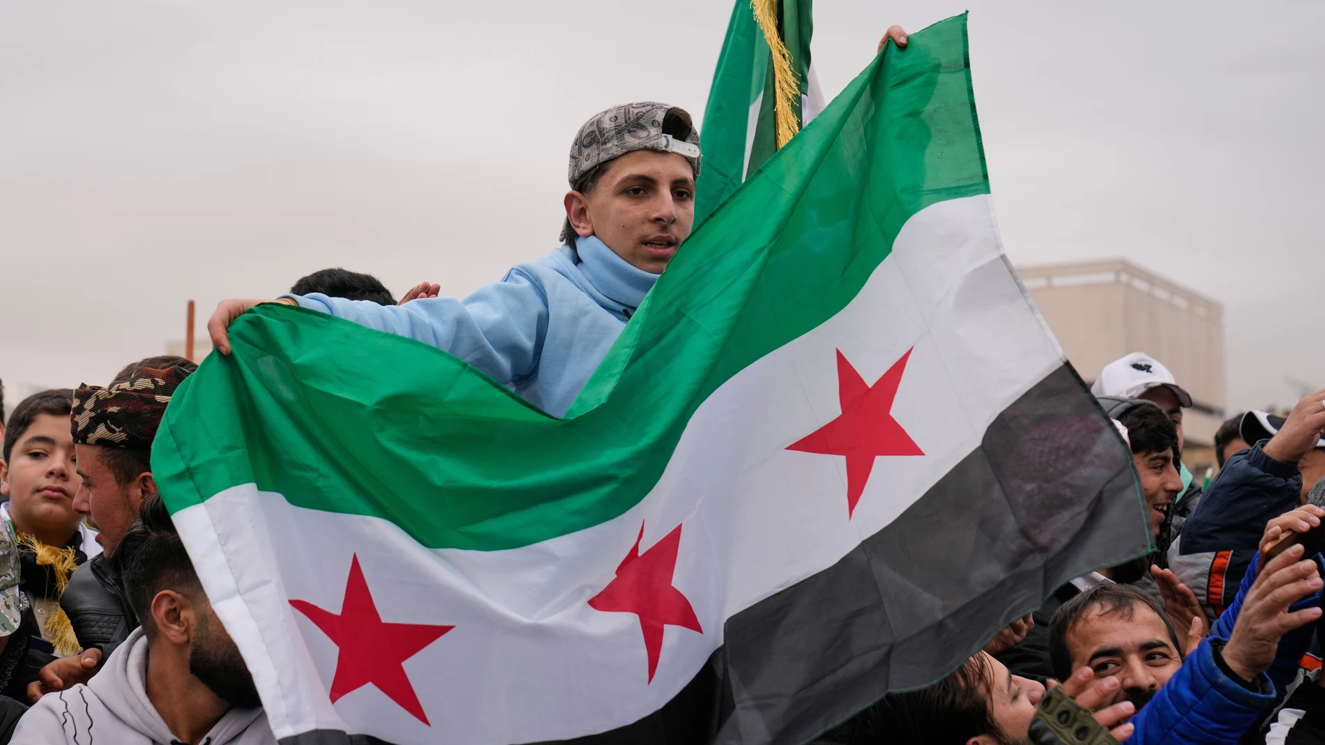 People wave the Syrian flag as they gather during celebrations marking the first anniversary of the ousting of former President Bashar Assad in Damascus, Syria, Monday, Dec. 8, 2025. (AP Photo/Hussein Malla)