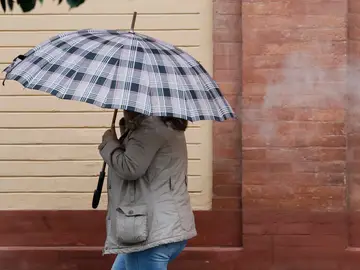 Lluvia en Sevilla GRAFAND2571. SEVILLA, 10/12/2025.-Una personas se resguarda de la lluvia con paraguas este miércoles en Sevilla cuando la Agencia Estatal de Meteorología (Aemet) prevé en Andalucía cielos muy nubosos o cubiertos, con precipitaciones moderadas en la mitad occidental, sin descartar que sean persistentes u ocasionalmente fuertes en el tercio occidental. EFE/José Manuel Vidal