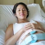 Mujer asi&aacute;tica china embarazada, en la cama del hospital 