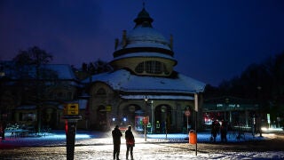 Passers-by stand in the light of a fire department help point in Berlin, Germany, Saturday, Jan. 3, 2025, during a power cut in south-west Berlin after a fire on a cable bridge. (Christoph Gollnow/dpa via AP)
