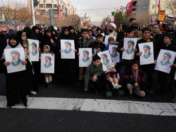 Personas sostienen carteles del l&iacute;der supremo iran&iacute;, el ayatol&aacute; Al&iacute; Jamenei, durante el funeral de un grupo de miembros de las fuerzas de seguridad que murieron durante las protestas antigubernamentales en Teher&aacute;n