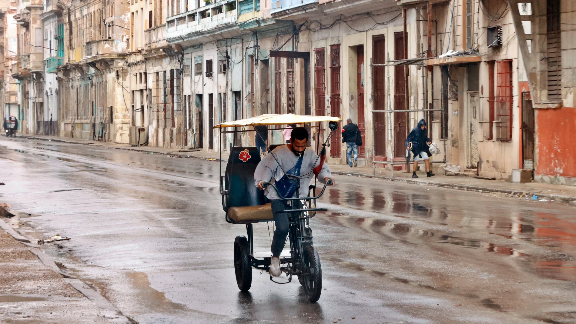 AME519. LA HABANA (CUBA), 01/02/2026.- Un hombre conduce un bicitaxi por una calle este domingo, en La Habana (Cuba). Inundaciones asociadas a un frente frío y fuertes marejadas para el litoral norte del occidente, con impacto probable en La Habana, se prevé un incremento de los vientos del noroeste y marejadas que podrían alcanzar intensidades fuertes en el litoral norte. EFE/ Ernesto Mastrascusa