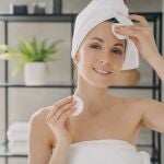 Mujer aplicando t&oacute;nico facial con discos de algod&oacute;n