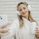 Mujer con total look en blanco y móvil y auriculares blancos