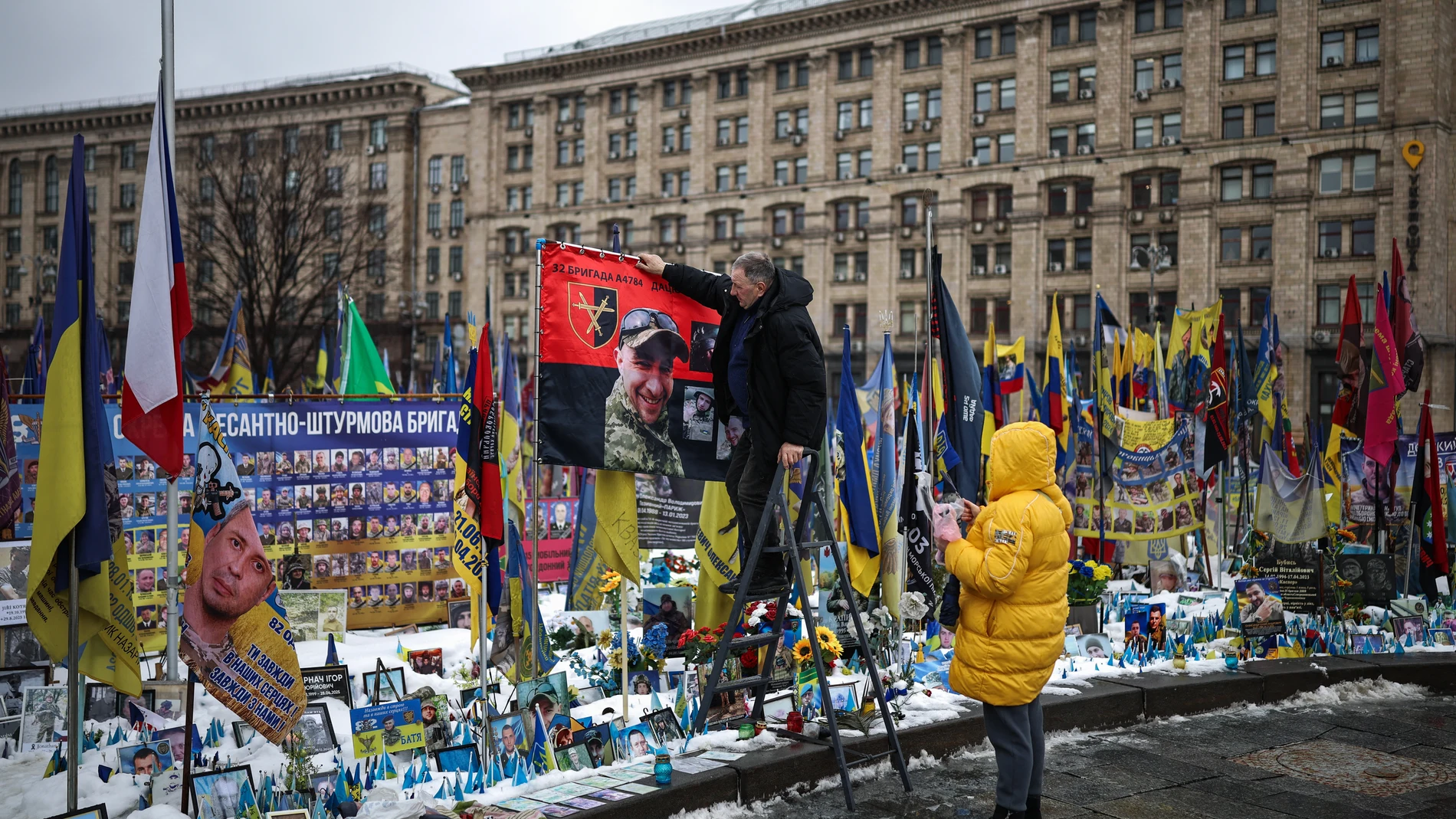 People make adjustments to a makeshift memorial to fallen Ukrainian and foreign soldiers in Independence Square in Kyiv on February 23, 2026, as the conflict with Russia reaches its four-year mark. Russia launched its full-scale invasion of Ukraine on February 24, 2022, unleashing the deadliest war in Europe since World War II.
