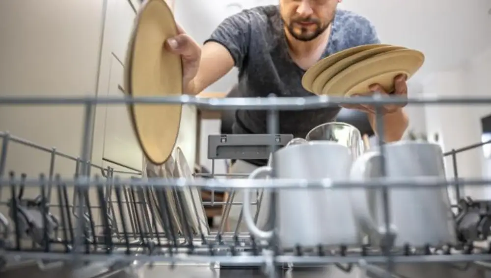 Hombre colocando los platos sucios en el lavavajillas