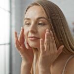 Mujer aplicando protector solar con color en el rostro