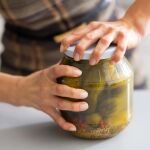 Una persona abre un bote de pepinillos