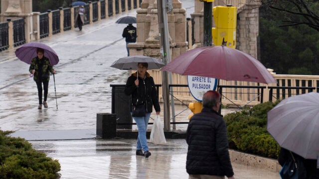 Varias personas caminan bajo la lluvia este viernes en Teruel. 