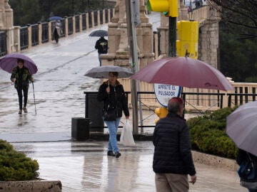 Varias personas caminan bajo la lluvia este viernes en Teruel. 