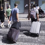 Dos turistas, con maletas, cruzan un paso de peatones