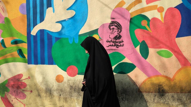 Un mujer camina frente a un grafiti del asesinado l&iacute;der supremo de Ir&aacute;n Al&iacute; Jamene&iacute; en las inmediaciones de la plaza la plaza Engelab (Revoluci&oacute;n) de Teher&aacute;n.