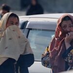 Dos mujeres observan mientras los equipos de rescate y funcionarios inspeccionan el lugar de un ataque a&eacute;reo ocurrido a &uacute;ltima hora del lunes en un hospital de rehabilitaci&oacute;n de adicciones en Kabul