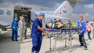 Un número indeterminado de muertos y 83 heridos en accidente de avión militar colombiano AME6865. BOGOTÁ (COLOMBIA), 23/03/2026.- Fotografía cedida por las Fuerzas Militares de Colombia (FF.MM.) que muestra a integrantes de organismos de rescate trasladando un herido de un accidente aéreo este lunes, en el Comando Aéreo de Transporte Militar (CATAM)en Bogotá (Colombia). El accidente de un avión Hércules C-130 de la Fuerza Aeroespacial Colombiana (FAC), que cayó a tierra tras despegar con 125 personas a bordo de la ciudad amazónica de Puerto Leguízamo, en el departamento del Putum...