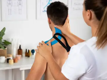 Una fisioterapeuta aplica un cinta kinesiológica Una fisioterapeuta aplica un cinta kinesiológica
