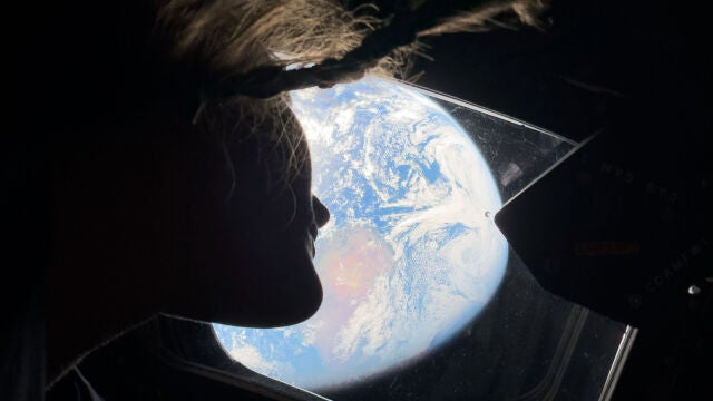 This image provided by NASA, astronaut and Artemis II mission specialist Christina Koch peers out of one of the Orion spacecraft's main cabin windows, looking back at Earth, as the crew travels towards the Moon on Thursday, April 2, 2026. (NASA via AP)