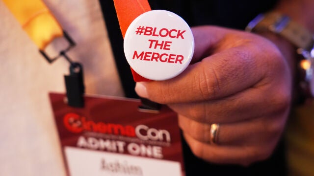 A CinemaCon attendee sports a pin expressing opposition to the proposed Paramount-Warner Bros. Discovery merger during CinemaCon 2026, Tuesday, April 14, 2026, at Caesars Palace, in Las Vegas. (AP Photo/Chris Pizzello)
