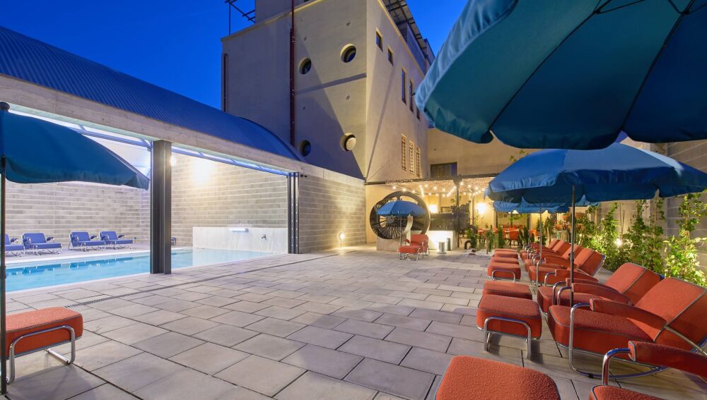 Fotografía del solarium y la piscina al anochecer