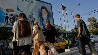 Iran Daily Life People cross the Islamic Revolution Street under a mural depicting a portrait of the late Iranian revolutionary founder Ayatollah Khomeini in downtown Tehran, Iran, Saturday, July 18, 2026. (AP Photo/Vahid Salemi)