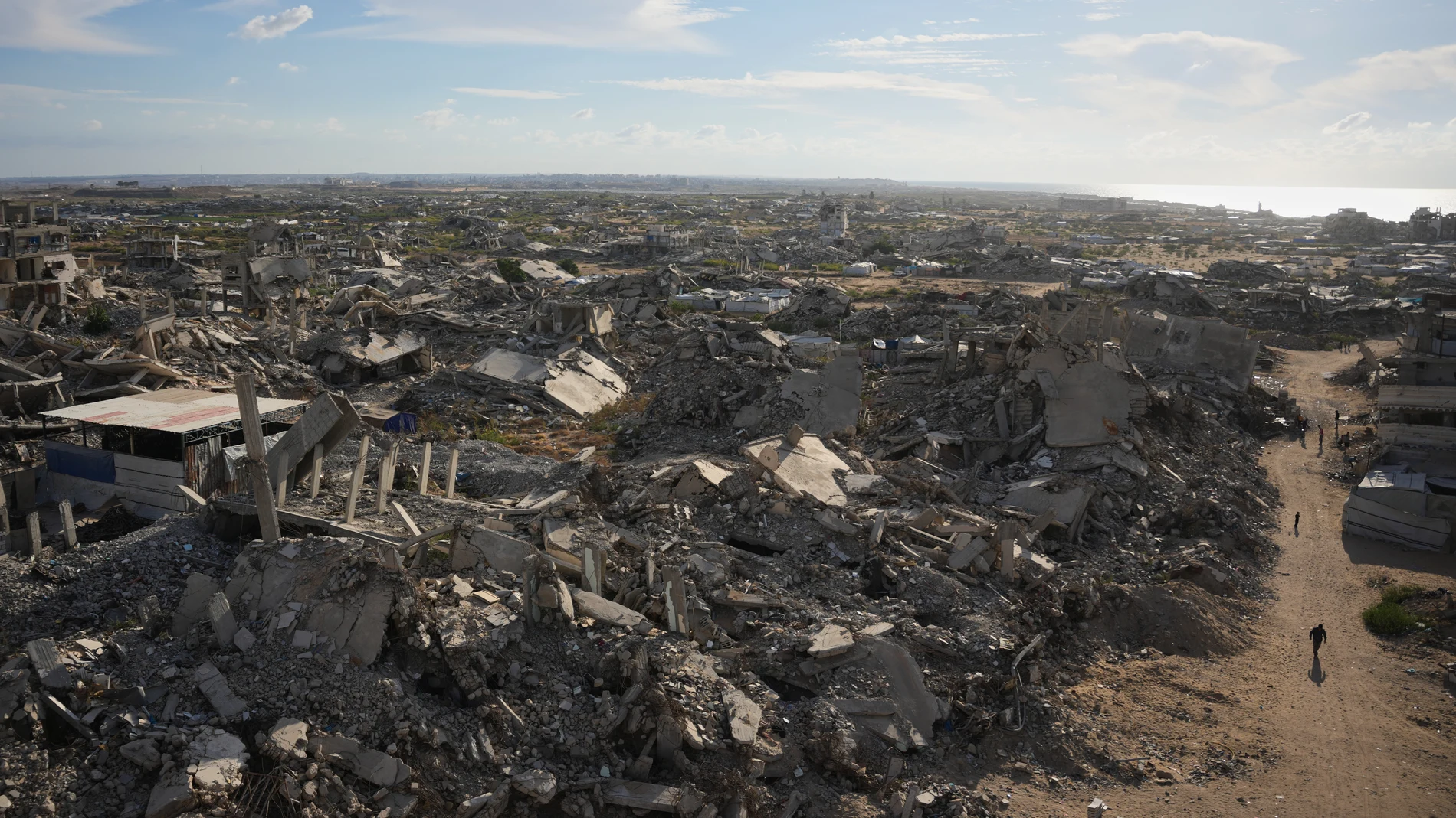 Israel Palestinians Gaza Palestinians walk past buildings destroyed during the Israel-Hamas war in Gaza City Tuesday, Oct. 20, 2026. (AP Photo/Abdel Kareem Hana)